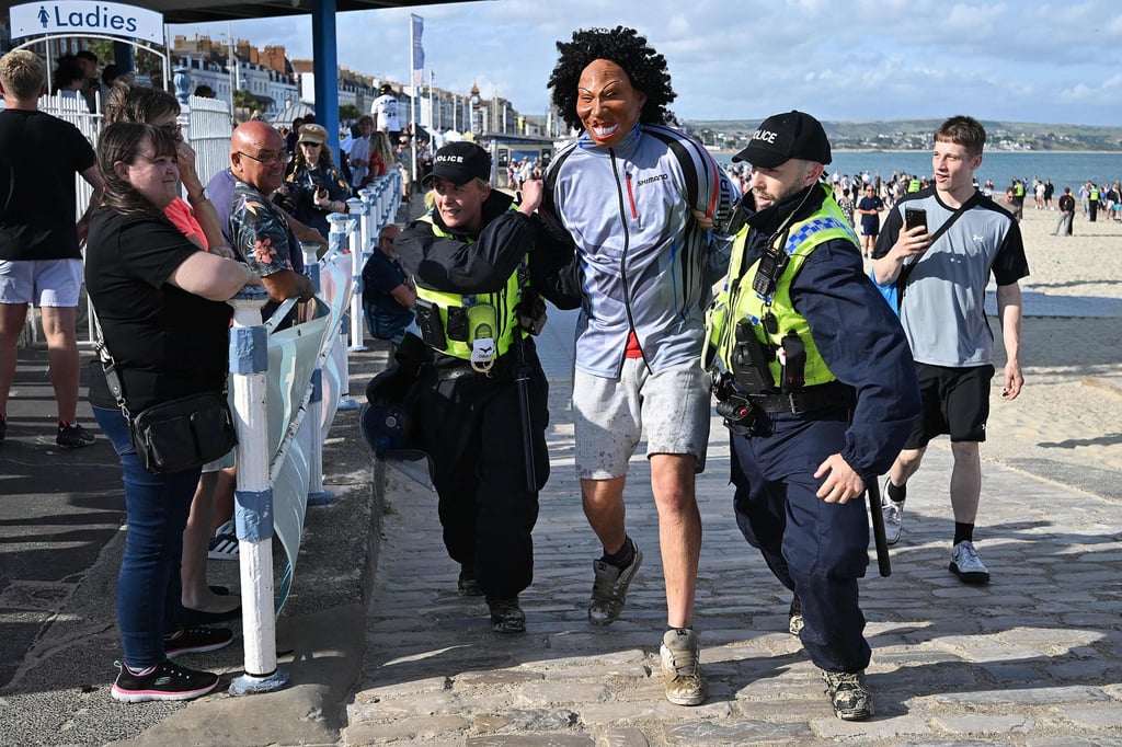 Police detain a protester in Weymouth, England on August 4. Photo: AFP