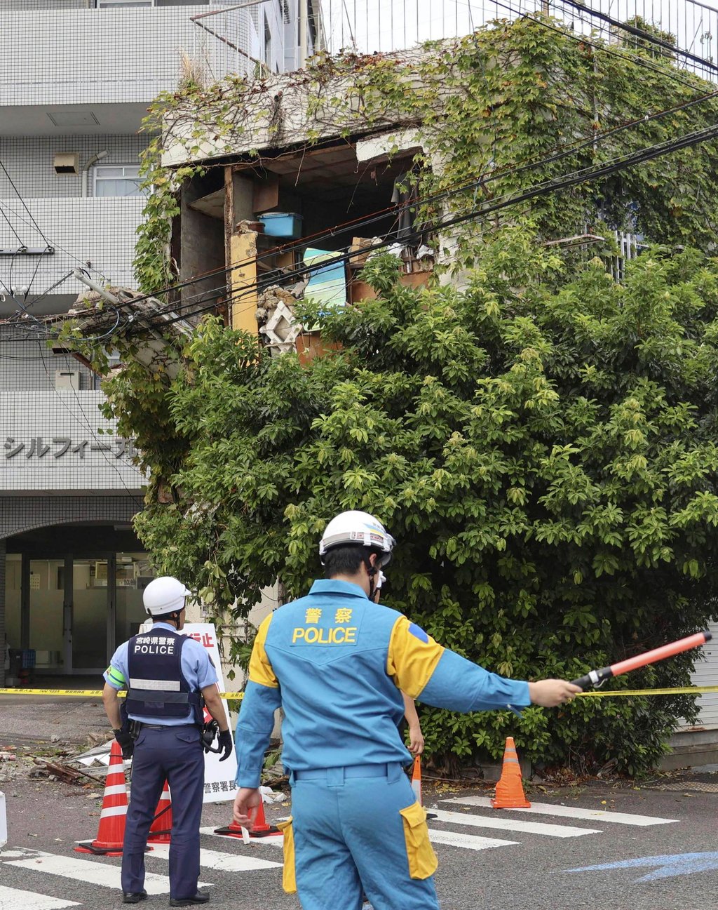 Police on guard outside a damaged building in the port city of Miyazaki after an earthquake struck offshore. Photo: AP Police on guard outside a damaged building in the port city of Miyazaki after an earthquake struck offshore. Photo: AP