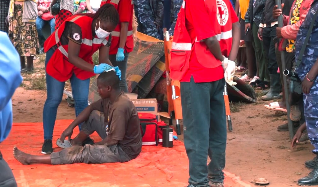 A man is helped by medical staff at the site of a collapsed landfill in Kampala, Uganda on Saturday. Photo: AP video via AP