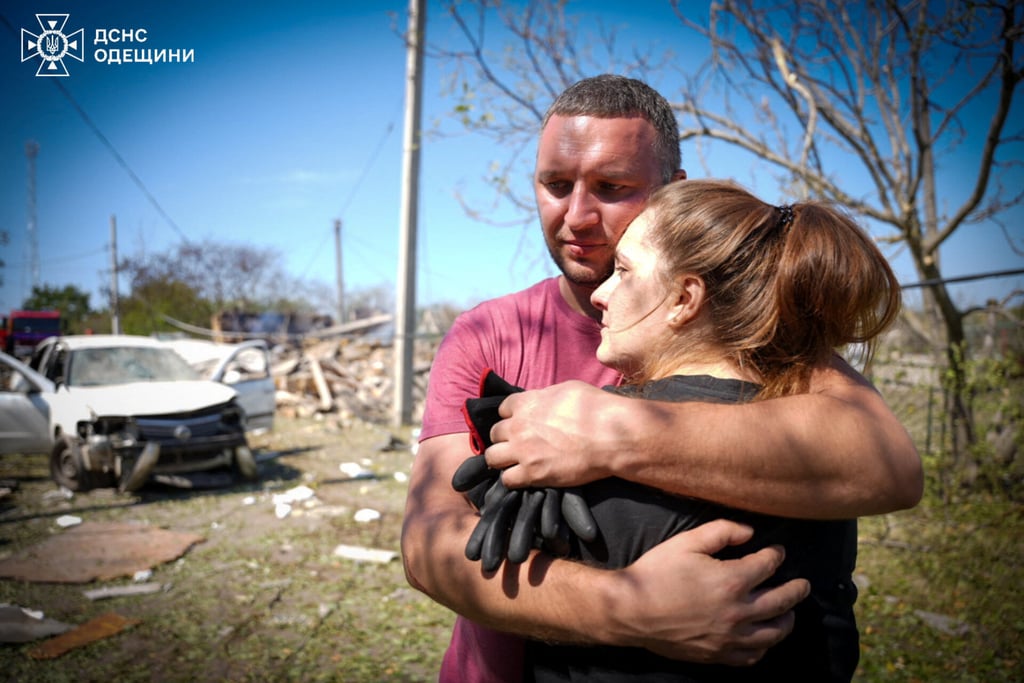 Local residents embrace each other at the site of a Russian missile strike. Photo: Press service of the State Emergency Service of Ukraine in Odesa region/Reuters