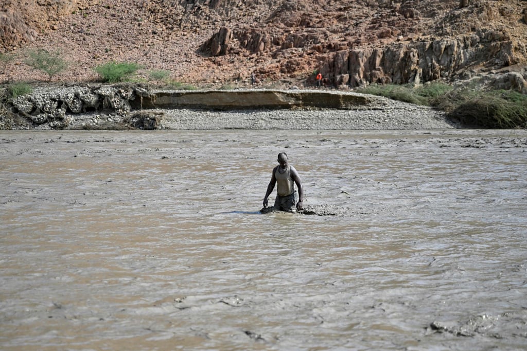 A man wades through muddy waters after the collapse of the Arbaat Dam. Photo: AFP