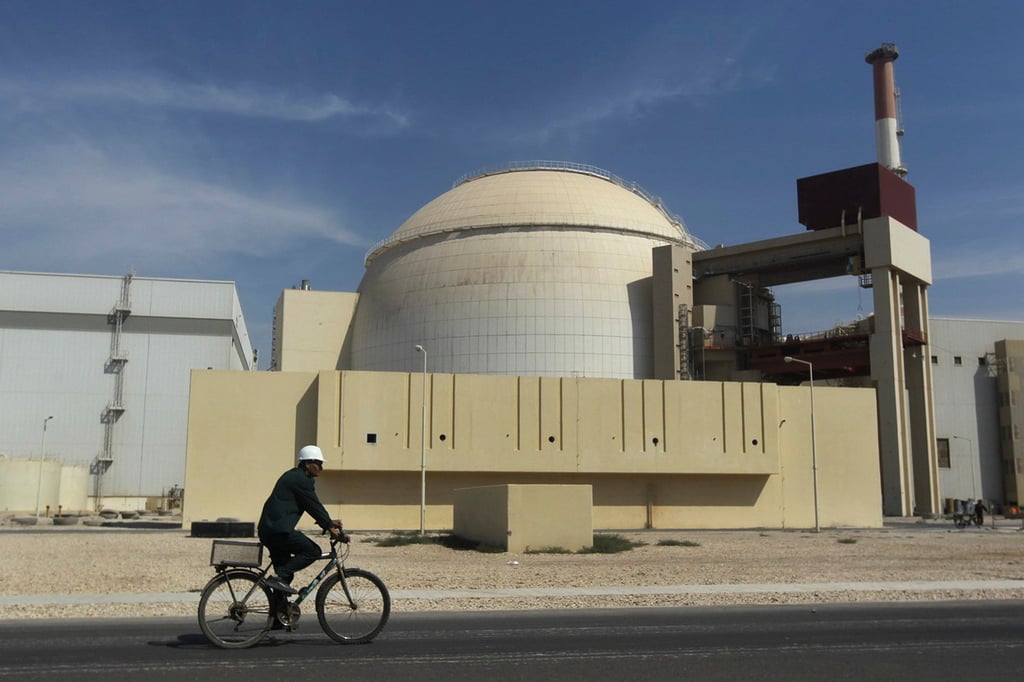 A worker rides a bike in front of the reactor building of the Bushehr nuclear power plant, just outside the southern city of Bushehr, Iran. Photo: AP