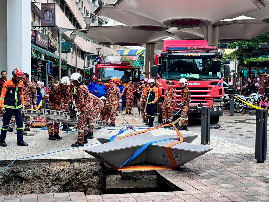 Rescue personnel prepare to enter the sinkhole in Kuala Lumpur on Friday after receiving reports that a woman had fallen into it. Photo: Fire and Rescue Department of Malaysia via AP Rescue personnel prepare to enter the sinkhole in Kuala Lumpur on Friday after receiving reports that a woman had fallen into it. Photo: Fire and Rescue Department of Malaysia via AP