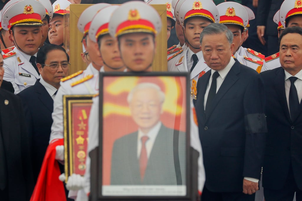 A member of Vietnam’s armed forces carries a portrait of the late Communist Party General Secretary Nguyen Phu Trong during his funeral in Hanoi last month as To Lam looks on. Photo: AP