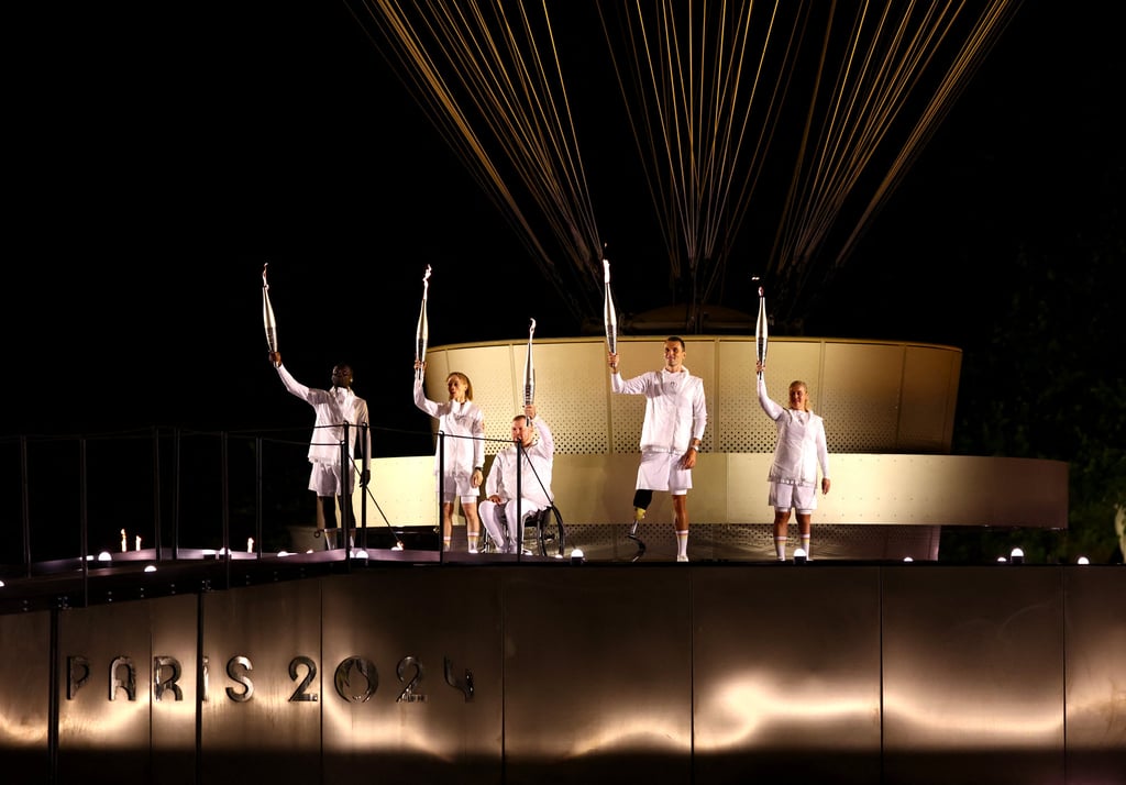 Charles-Antoine Kouakou, Nantenin Keita, Fabien Lamirault, Alexis Hanquinquant and Elodie Lorandi raise torches next to the Olympic cauldron. Photo: Reuters