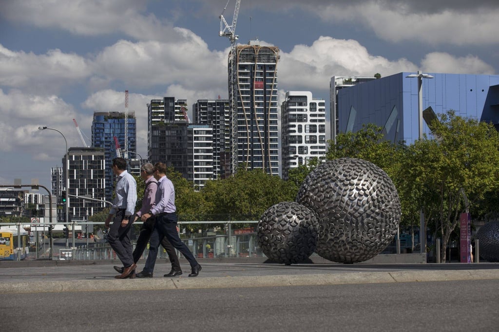 Pedestrians pass a residential building under construction in Brisbane, capital of Queensland, in Australia. Photo: Bloomberg