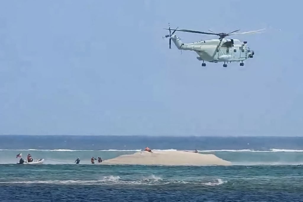 A Chinese helicopter hovers as Philippine scientists inspect a cay near Thitu Island in March. Photo: Philippine Coast Guard / AFP