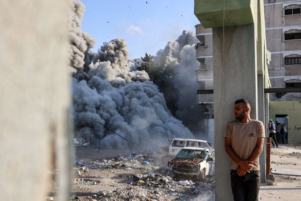 A man takes cover behind a column as an explosion creates smoke and dust during an Israeli strike targeting a school on the outskirts of Gaza City on Sunday. Photo: AFP