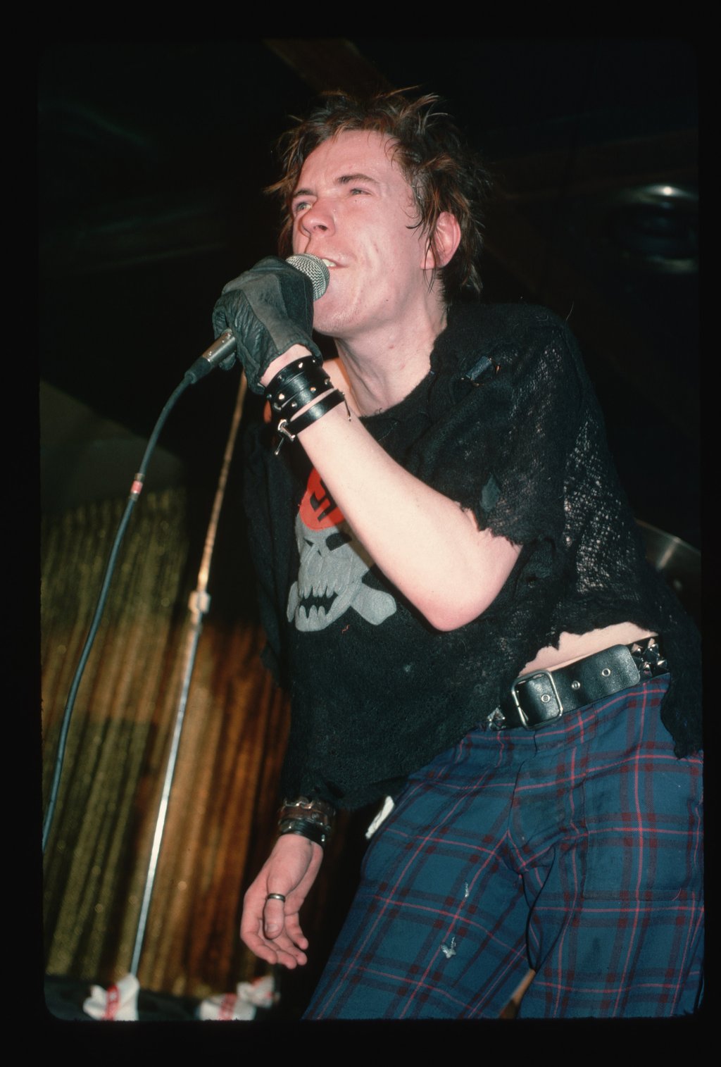 Sex Pistols singer Johnny Rotten on stage during the Sex Pistols’ 1978 tour wearing plaid pants and a black glove. Photo: Getty Images