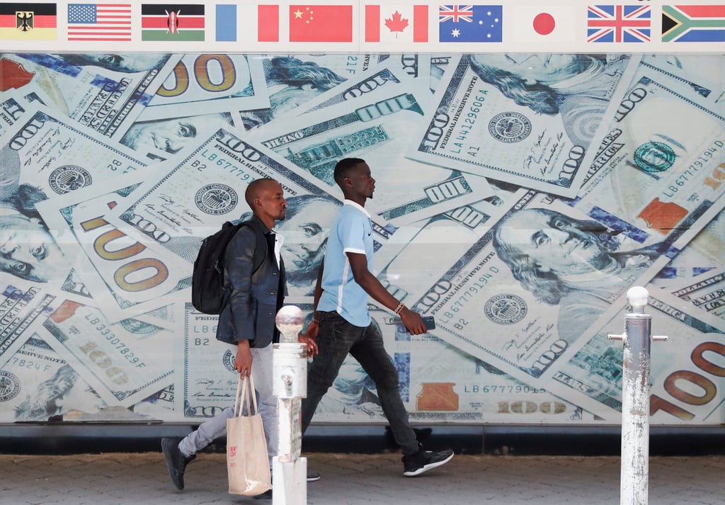 People walk past an image of US dollar bills outside a currency exchange bureau in downtown Nairobi, Kenya, on February 16. Photo: Reuters