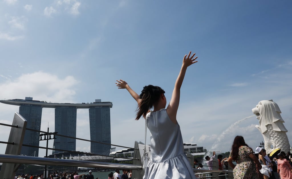 A tourist poses for photos at the Merlion Park in Singapore. Since February, Chinese travellers have enjoyed visa-free access to the city state. Photo: EPA-EFE