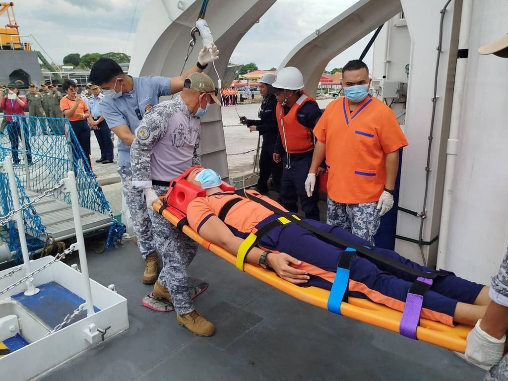 A member of the Philippine coastguard requiring medical care is carried off the BRP Teresa Magbanua after its arrival at a port in Puerto Princesa, Palawan. Photo: Philippine Coast Guard/Handout via AFP