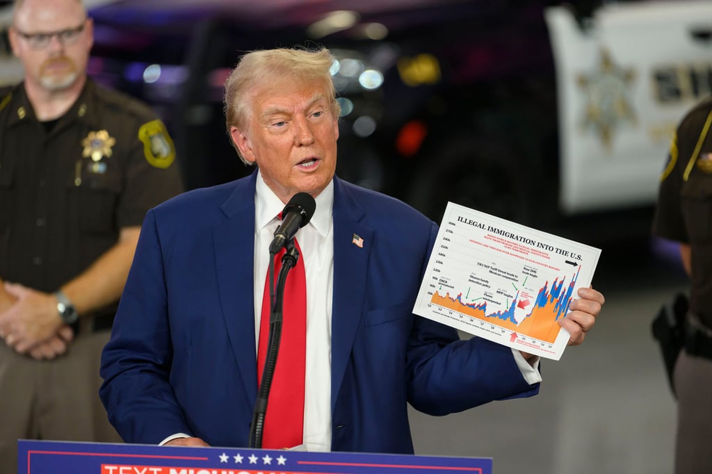 Former US president Donald Trump holds up an immigration chart while speaking at a campaign event in Howell, Michigan, in August. Photo: The Detroit News via TNS