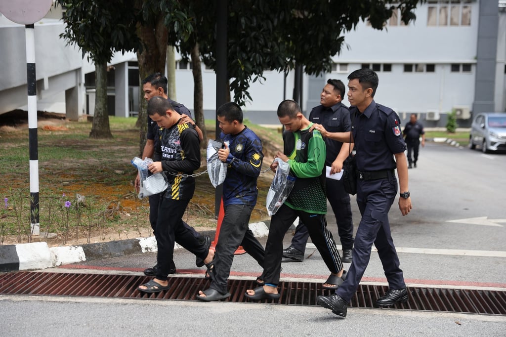 Malaysian police officers escort three members of Global Ikhwan Services and Business Holdings as they depart after facing charges at a court in Seremban on September 19. Photo: EPA-EFE