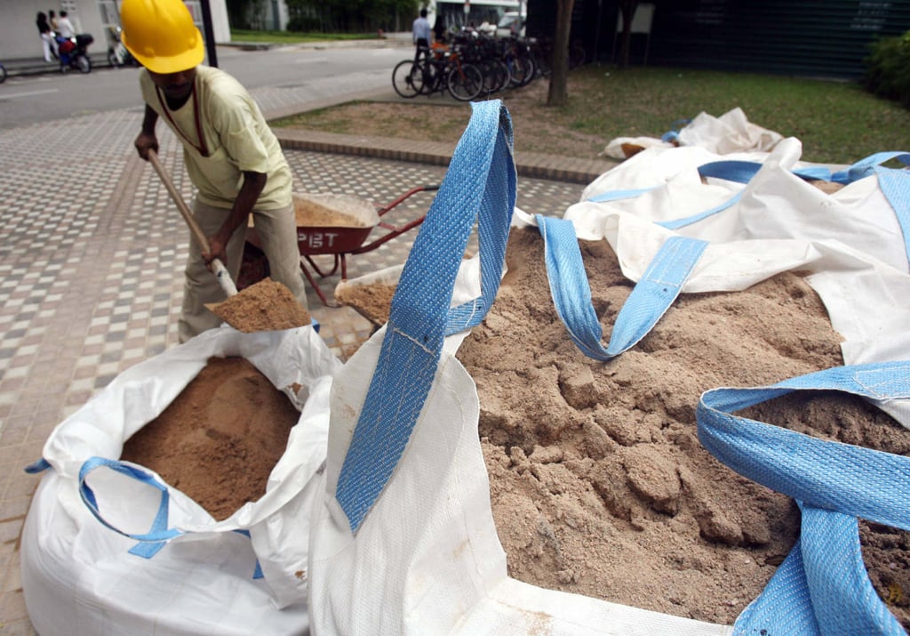 A worker fills a wheelbarrow with sand near a construction site in Singapore in 2007. Photo: AFP A worker fills a wheelbarrow with sand near a construction site in Singapore in 2007. Photo: AFP