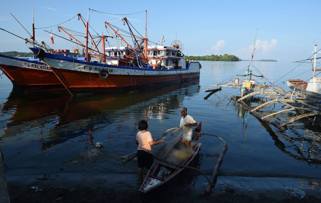 Filipino fishers fix nets next to a fishing fleet at the port in Masinloc, Zambales province. Photo: AFP
