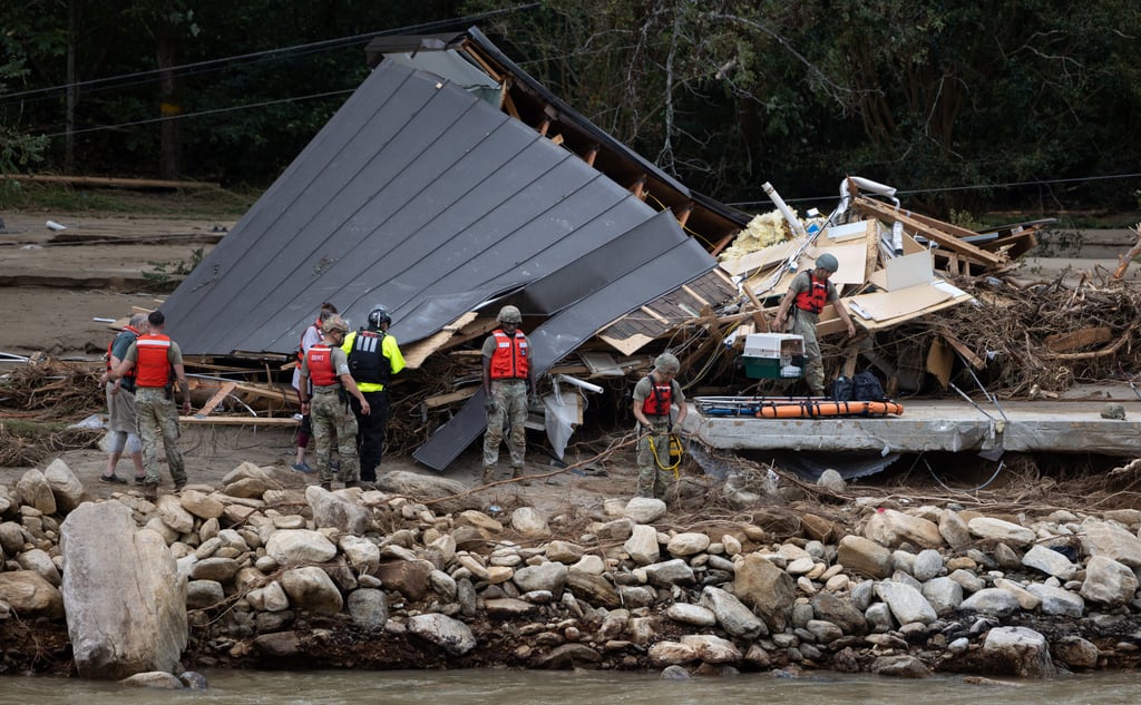 People and a dog are escorted to a rescue boat in Chimney Rock, North Carolina on Sunday. Photo: Khadejeh Nikouyeh / The Charlotte Observer/Handout via Reuters