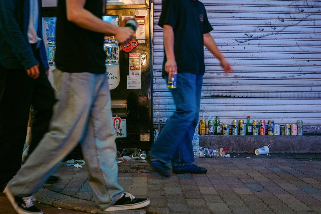 Pedestrians holding alcoholic drinks walk past litter in the Shibuya district of Tokyo last month. Photo: Bloomberg