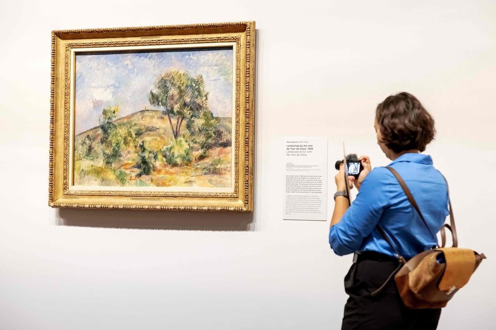 A woman looks at Landscape near Aix with Tour de Cesar, by Paul Cézanne, at the Van Gogh Museum, in Amsterdam, the Netherlands, on October 9, 2024. Photo: AFP