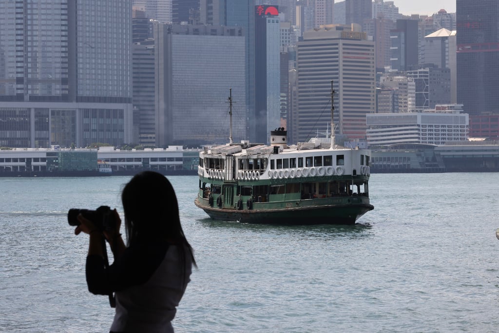 A woman takes photographs along Victoria Harbour. Trami is expected to gradually move towards the vicinity of Hainan Island. Photo: Dickson Lee