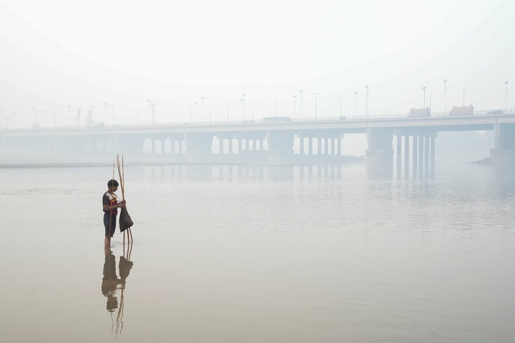 A fisherman sets up a trap in Lahore, with the bridge over the River Ravi in the background, amid heavy smog on Tuesday. Photo: Reuters