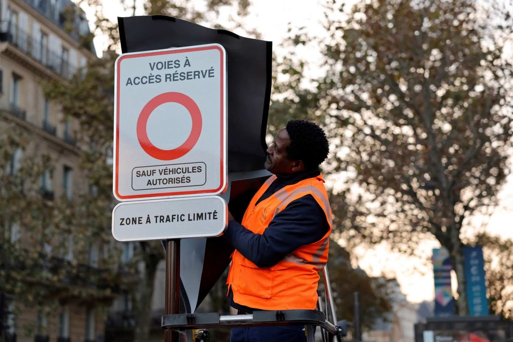 A city employee unveils a traffic sign indicating the limited traffic zone in the central core of the French capital banning vehicles from transiting through it. Photo: AFP A city employee unveils a traffic sign indicating the limited traffic zone in the central core of the French capital banning vehicles from transiting through it. Photo: AFP