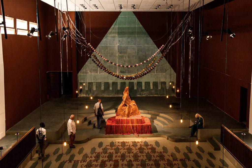 People walk through an art installation, A Palace in Pieces including Mountain Mama, by Kenyan artist Wangechi Mutu, at the Dakar Biennale. Photo: AFP