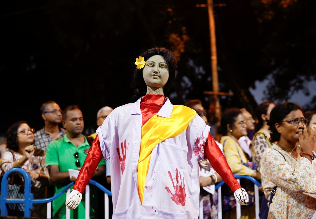 People stand behind an idol wearing a doctor’s coat as they attend a protest condemning the rape and murder of a trainee medic at a government-run hospital in Kolkata. Photo: Reuters People stand behind an idol wearing a doctor’s coat as they attend a protest condemning the rape and murder of a trainee medic at a government-run hospital in Kolkata. Photo: Reuters