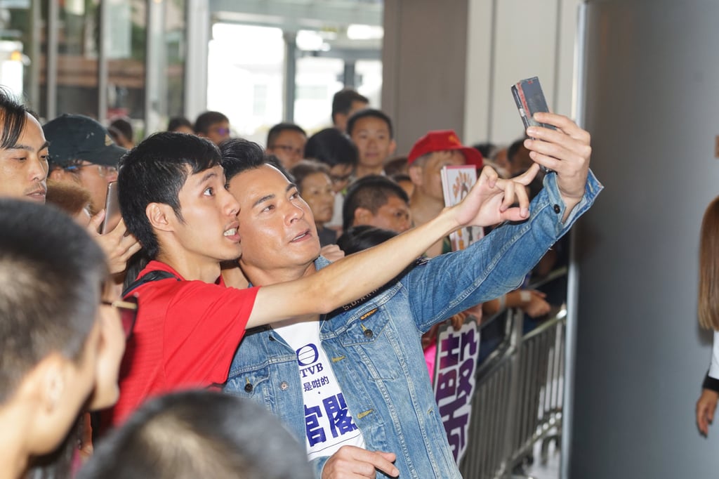 Hong Kong actor Ben Wong Chi-yin (centre) taking a selfie with a fan in Hong Kong. Photo: Getty Images