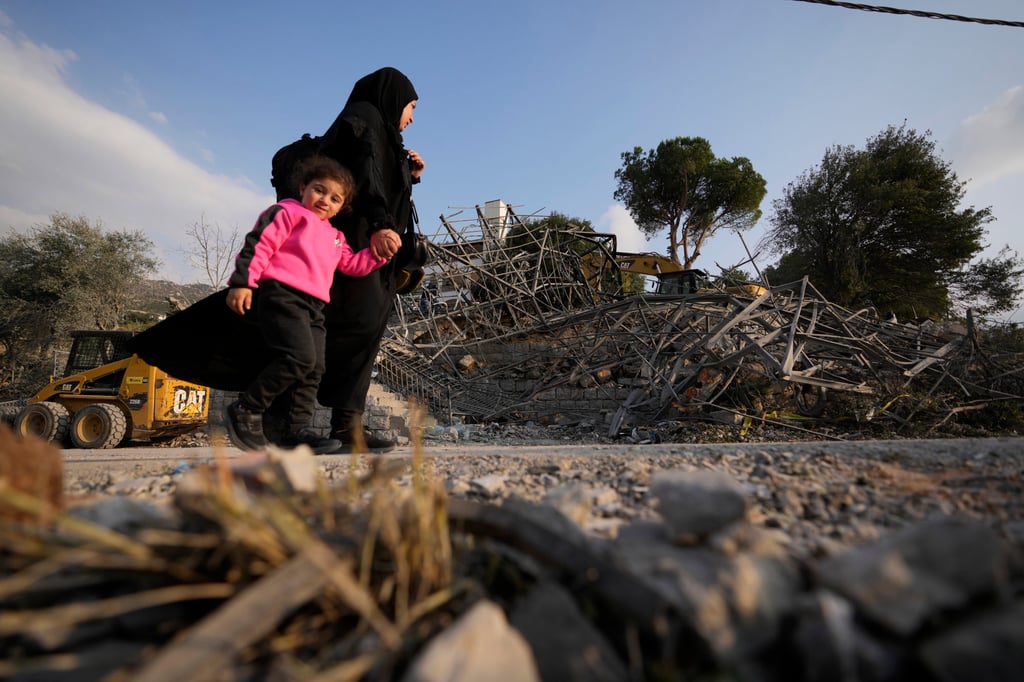 A woman with a child pass the site where an Israeli strike hit a house in Aalmat village, northern Lebanon on Sunday. Photo: AP A woman with a child pass the site where an Israeli strike hit a house in Aalmat village, northern Lebanon on Sunday. Photo: AP