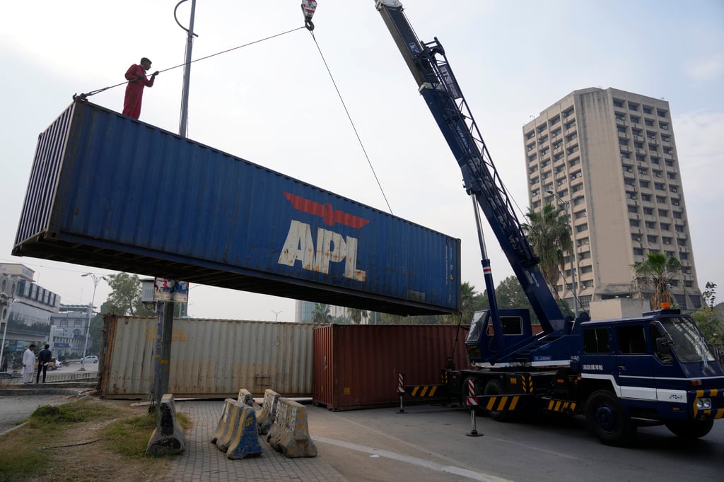 Workers place shipping containers to close a road ahead of a planned rally by supporters of imprisoned former prime minister of Pakistan Imran Khan’s Pakistan Tehreek-e-Insaf party, in Islamabad, Pakistan, on Saturday. Photo: AP