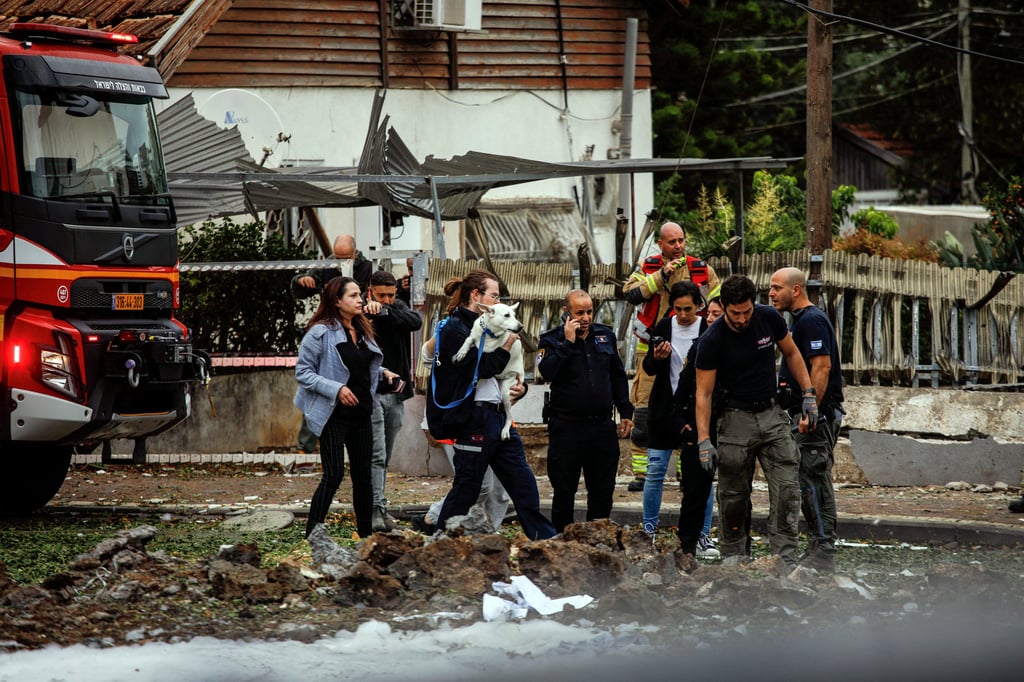 Medical personnel rescue a dog at the scene where a projectiles fell in Petah Tikva, Israel. Photo: Reuters Medical personnel rescue a dog at the scene where a projectiles fell in Petah Tikva, Israel. Photo: Reuters