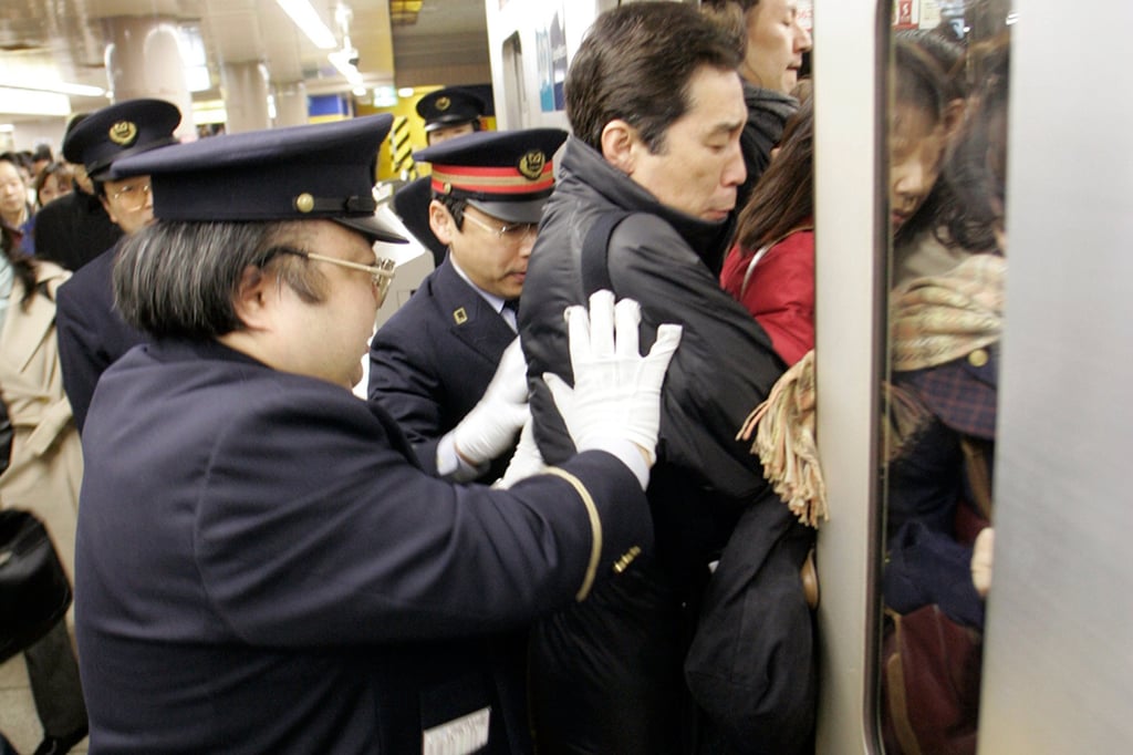 Staff push a passenger into a crowded subway train during rush hour in Tokyo. Photo: Reuters