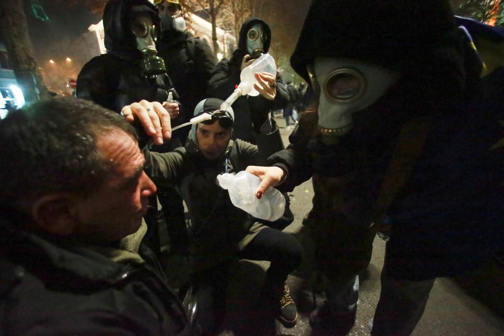 Demonstrators help treat a man who was injured by tear gas. Photo: AP Demonstrators help treat a man who was injured by tear gas. Photo: AP