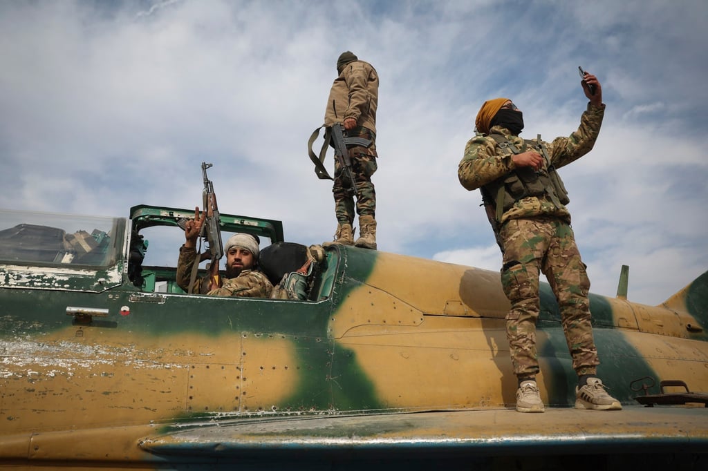 Rebel fighters stand atop a seized Syrian Air Force fighter plane at the Hama military airport on Friday. Photo: AP