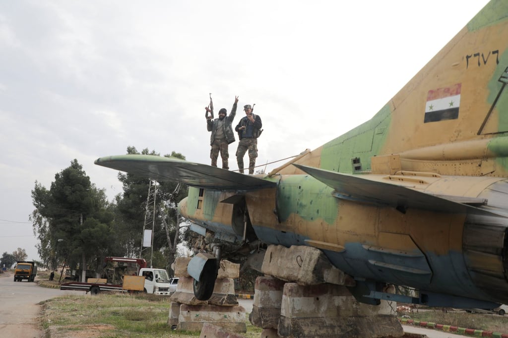 A rebel fighter gives the victory sign while standing on a military aircraft that belonged to forces loyal to the Assad government at Hama’s military airport on Saturday. Photo: Reuters