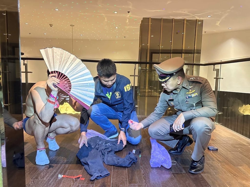 Police officers examine attendees’ clothing, finding narcotics concealed in one participant’s trousers during the raid at a party in Bangkok on December 8. Photo: Thonglor Police