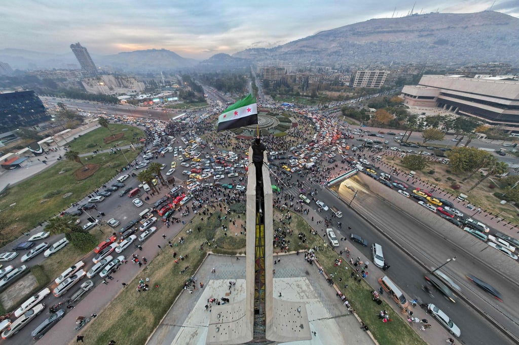 A man waves the independence-era Syrian flag at Damascus’ central Umayyad Square on Wednesday. Photo: AFP