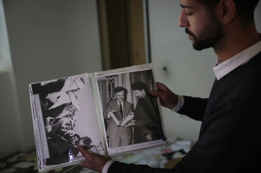 A man shows old pictures of the late Syrian President Hafez Assad in a ransacked private residence in Damascus. Photo: AP A man shows old pictures of the late Syrian President Hafez Assad in a ransacked private residence in Damascus. Photo: AP