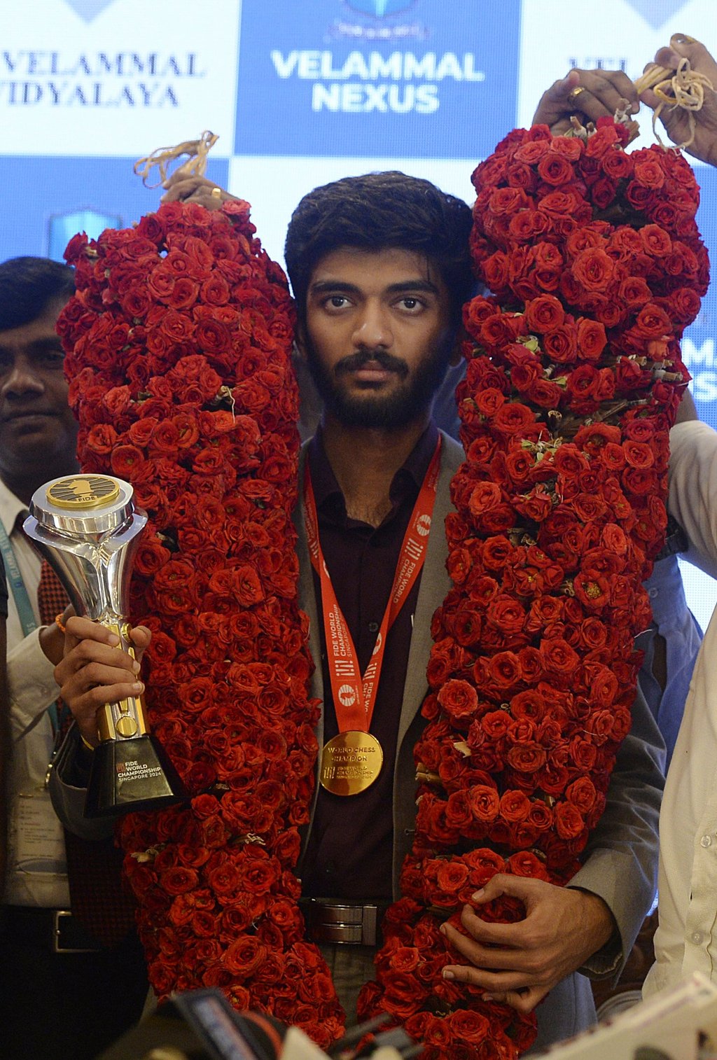 Gukesh Dommaraju has garlands of flowers draped around his neck as he brandishes his trophy. Photo: AP