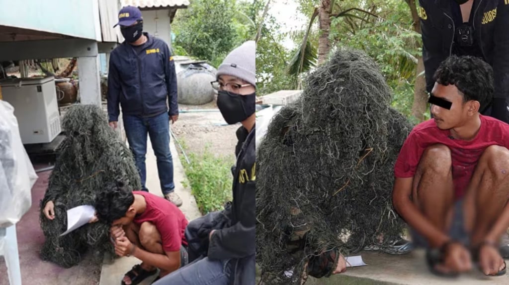 The suspect is pictured beside the camouflaged officer and his colleagues after his arrest. Photo: Khaosodejan The suspect is pictured beside the camouflaged officer and his colleagues after his arrest. Photo: Khaosodejan