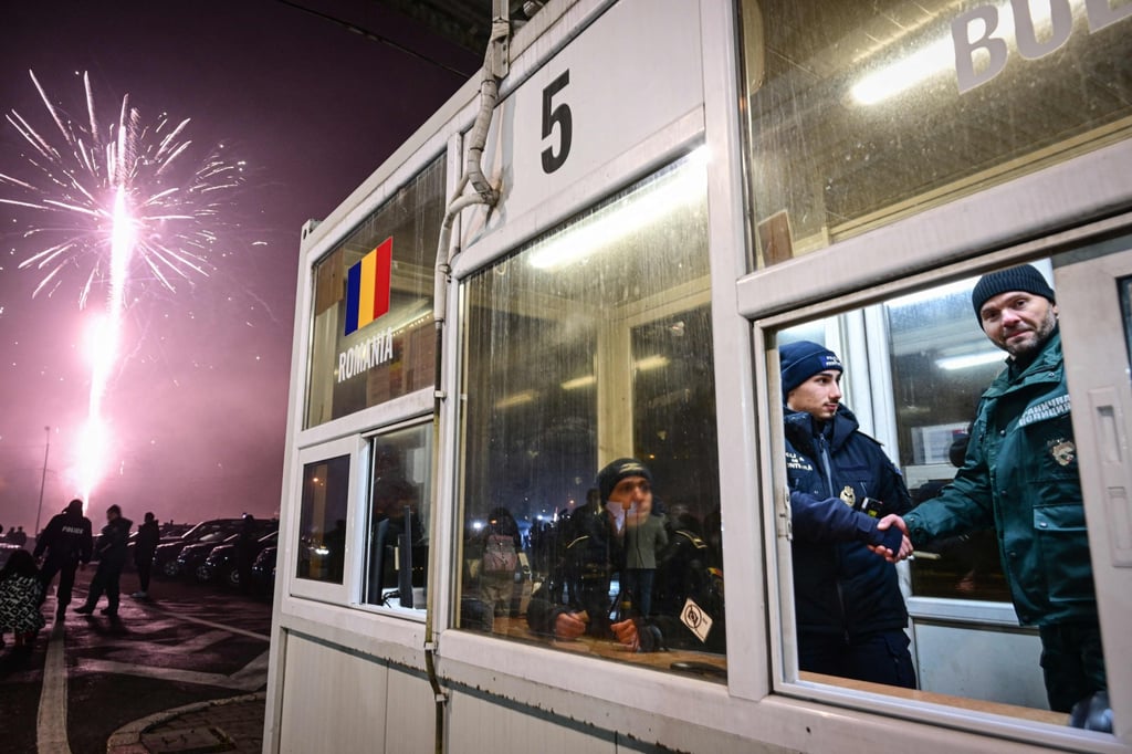 Romanian and Bulgarian police officers shake hands at a check point. Phot: AFP