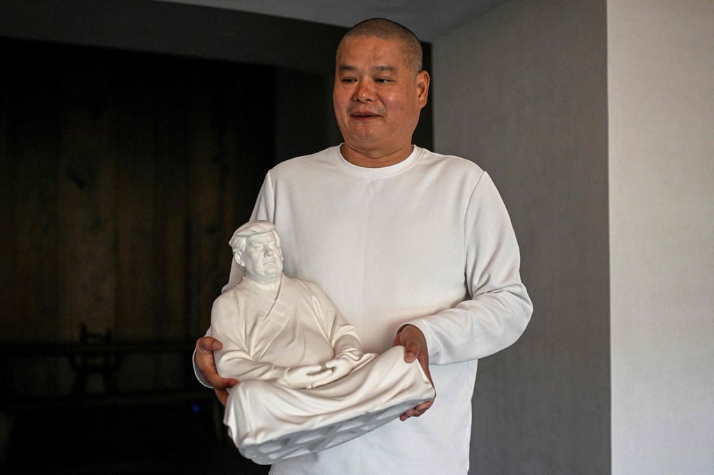 Artist Hong Jinshi holds one of his Buddha-like sculptures of Donald Trump. Photo: AFP Artist Hong Jinshi holds one of his Buddha-like sculptures of Donald Trump. Photo: AFP