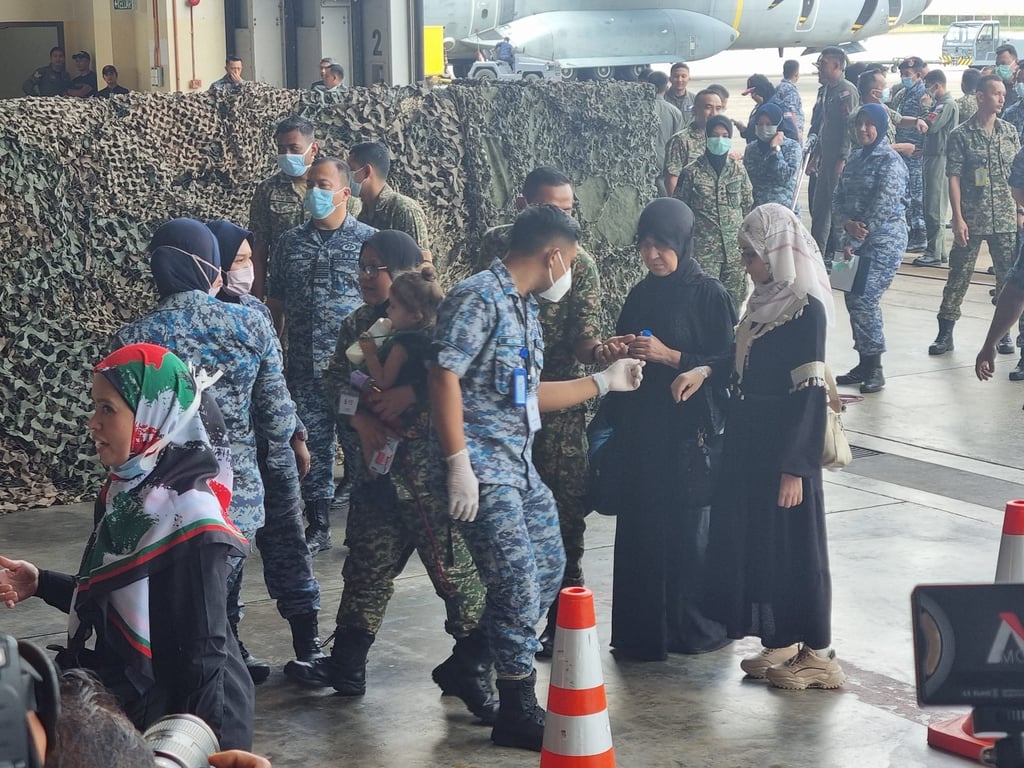 Malaysian armed forces personnel escort patients and families into a field hospital set up in a hangar at the Subang air force base on their arrival from Egypt in August 2024. Photo: Joseph Sipalan