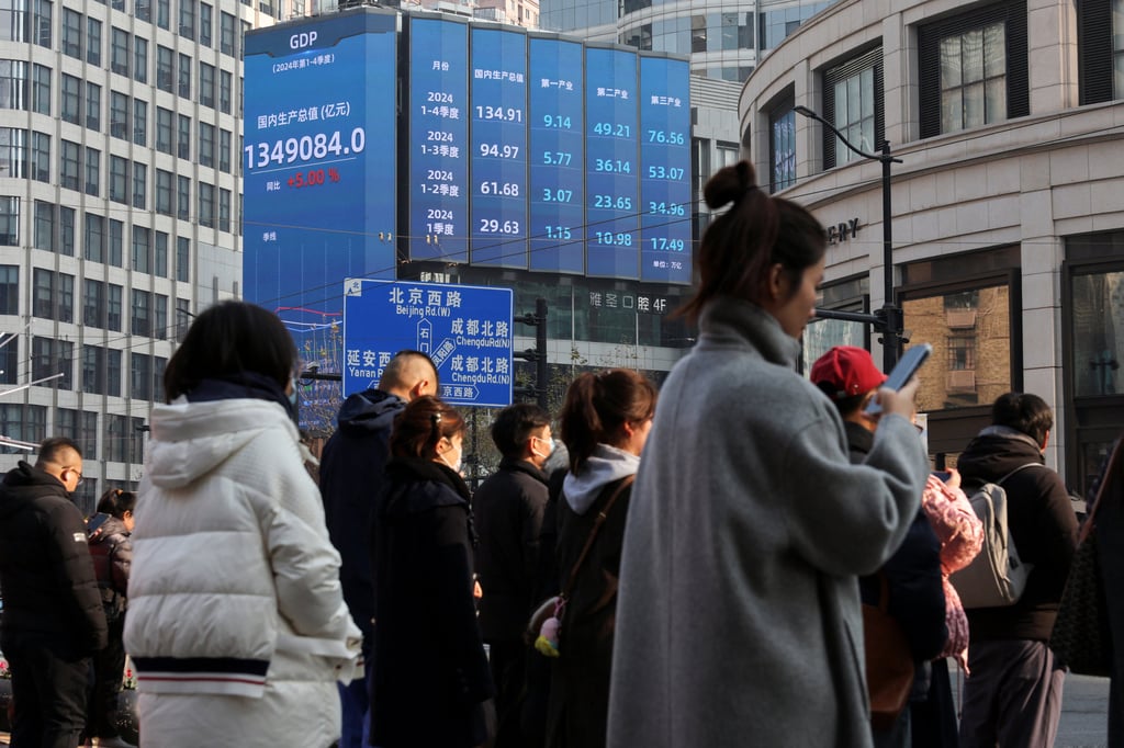 Pedestrians wait to cross a street in Shanghai on Tuesday as an electronic sign shows China’s economic growth in 2024. Photo: Reuters Pedestrians wait to cross a street in Shanghai on Tuesday as an electronic sign shows China’s economic growth in 2024. Photo: Reuters