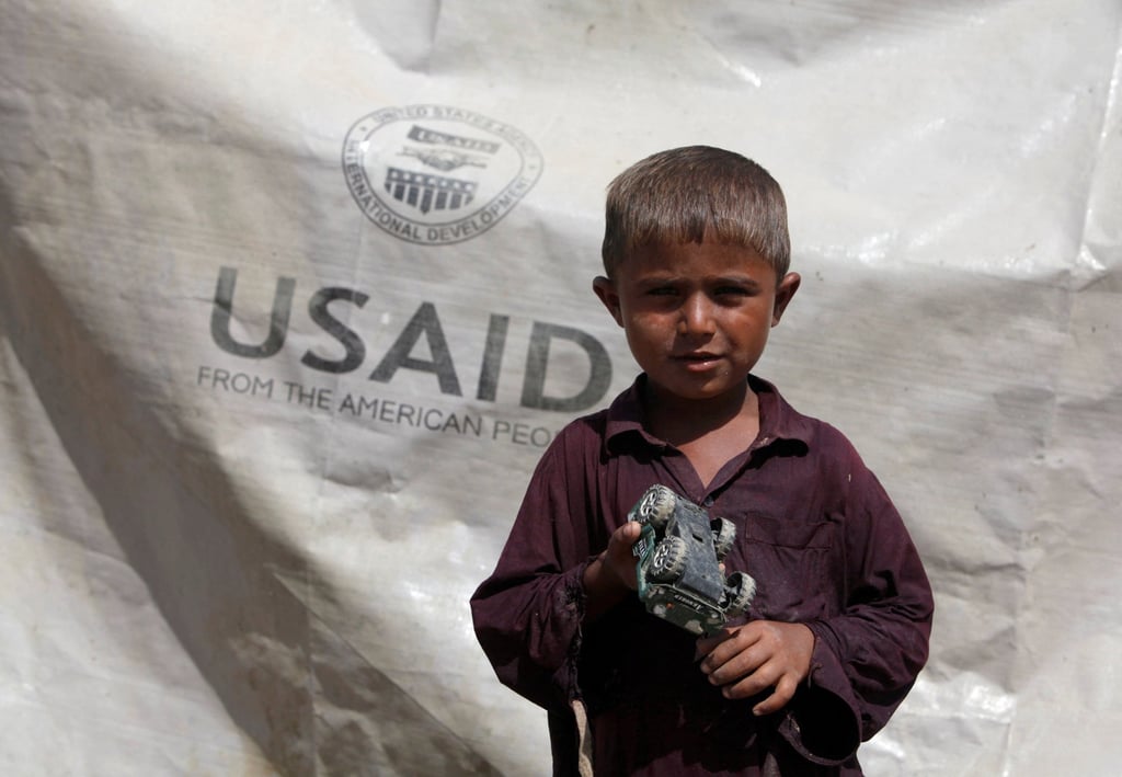 Sajad, 7, who has been displaced by flooding, holds his toy jeep outside his family tent with the weather sheet donated by USAID, in Pakistan’s Sindh province in 2010. Photo: Reuters