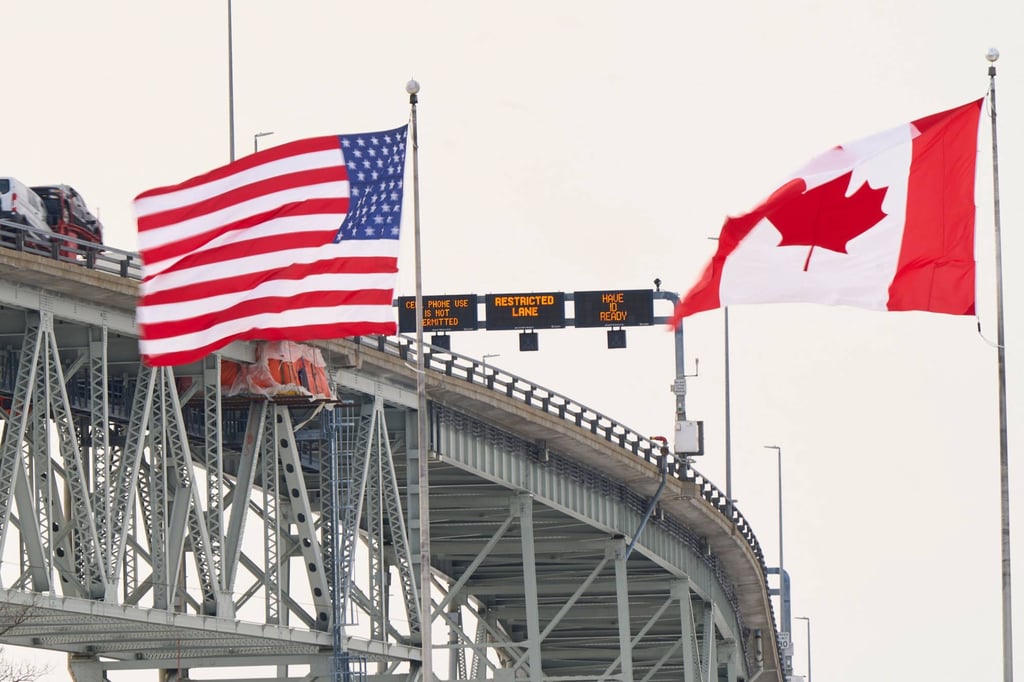 The US and Canadian flags fly on the US side of the Saint Clair River near the border crossing between Ontario and Michigan. Photo: AFP