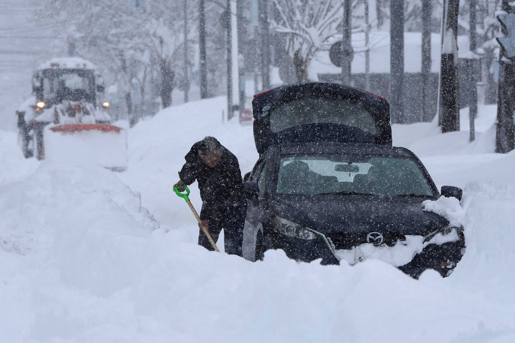 A man tries to dig his car out of the snow using a shovel in Obihiro city on Tuesday. Photo: Jiji Press/AFP