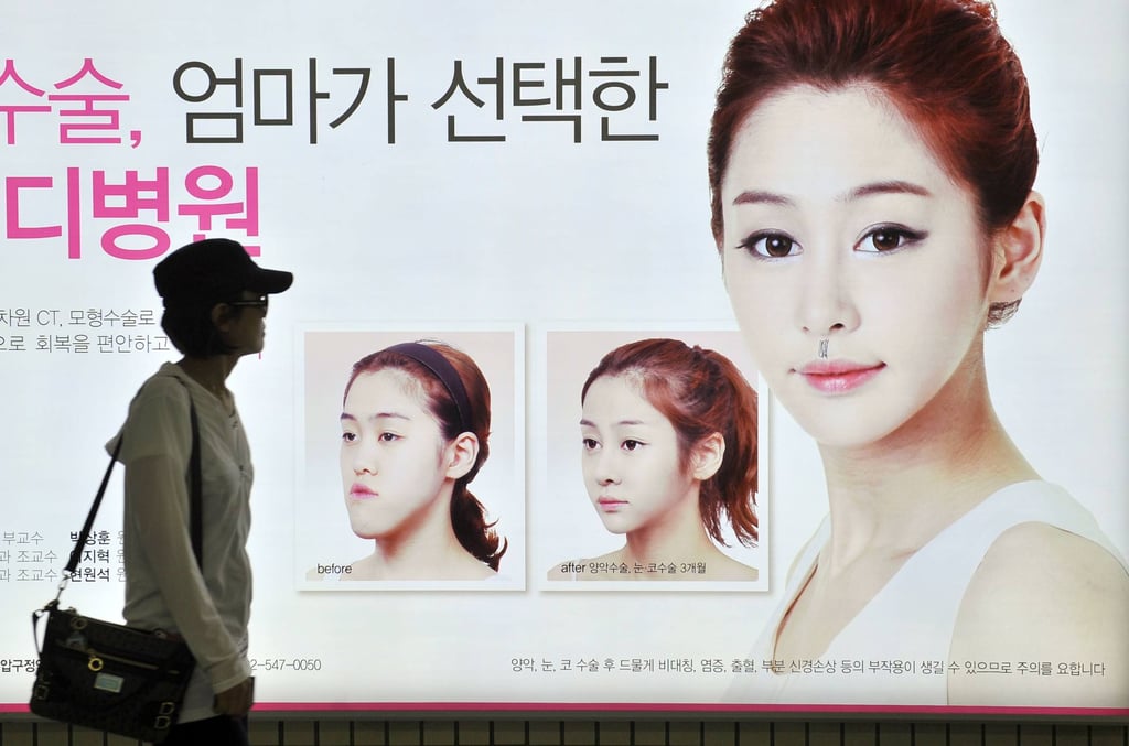 A South Korean woman walking past a street billboard advertising double-jaw surgery at a subway station in Seoul. Photo: AFP