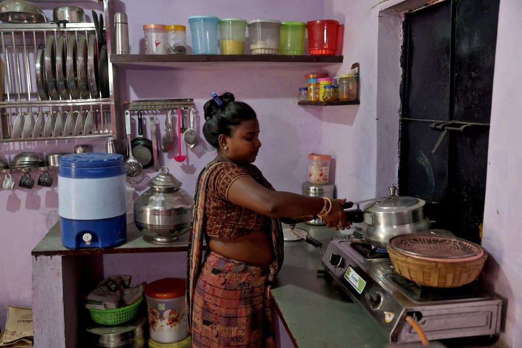 Nehal Vijaybhai Bhil, whose one-room house’s rooftop has been coated with liquid-applied membrane, cooks in the kitchen at a slum in Ahmedabad, India, on March 7. Photo: Reuters
